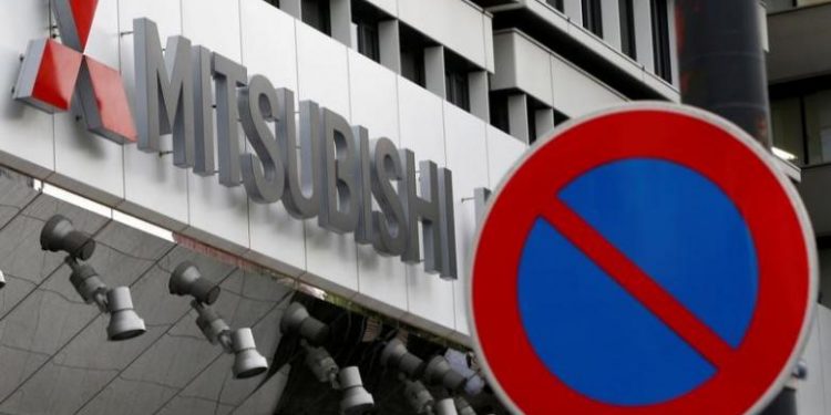 The company logo of Mitsubishi Motors is seen behind a traffic sign at its headquarters in Tokyo, Japan, August 2, 2016. REUTERS/Kim Kyung-Hoon