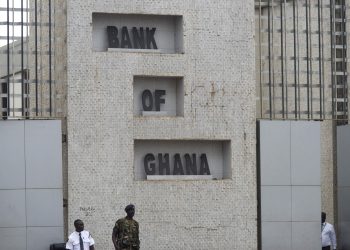 A soldier and policemen stand guard outside the headquarters of Ghana's central bank, also known as the Bank of Ghana, in Accra, Ghana, on Tuesday, Sept. 20, 2016. Ghana's central bank expects mergers and acquisitions among lenders to increase as regulators prepare new rules that will boost the amount of cash that they need to set aside. Photographer: Ty Wright/Bloomberg